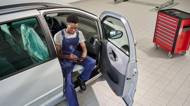 Un empleado de Volkswagen  sentado en el asiento de pasajero delantero con la puerta abierta