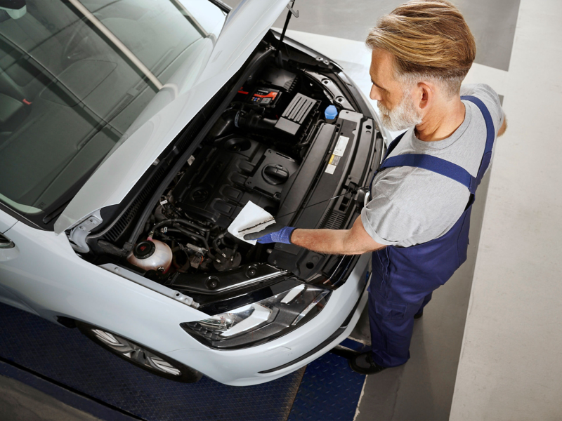 Draufsicht auf VW Sharan 2 mit geöffneter Motorhaube, VW Servicemitarbeiter misst Ölstand