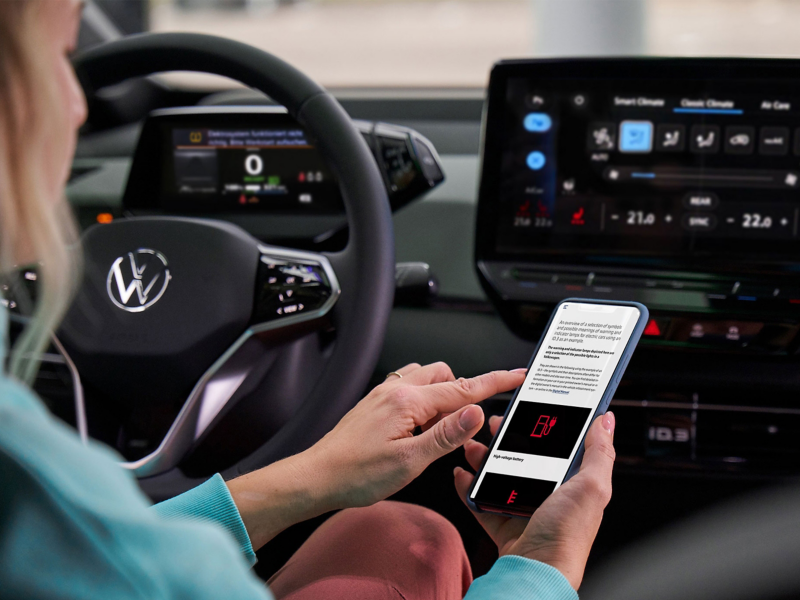 Una clienta se sienta al volante de un coche VW y se informa sobre las luces de advertencia