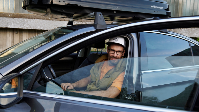 Mann sitzt auf Fahrersitz eines VW Passat B8, Fahrertür ist offen