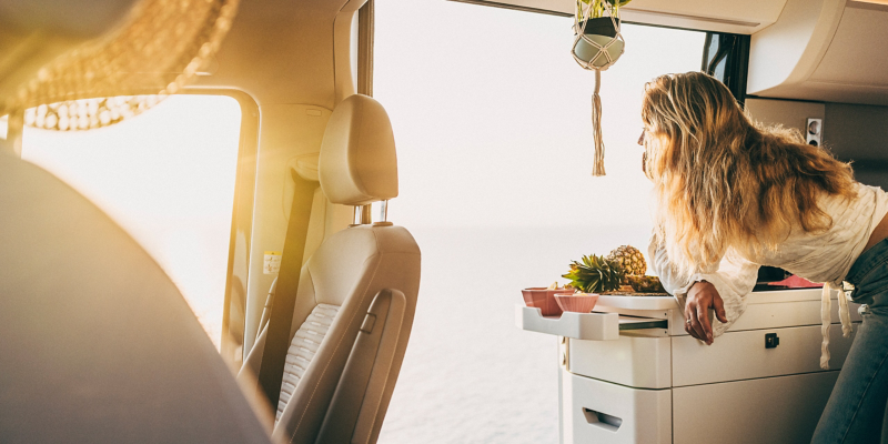 Une femme est allongée sur la cuisine d’un Grand California avec la porte latérale ouverte.
