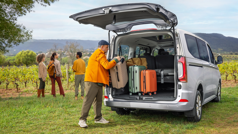 Ein Mann holt Koffer aus dem Kofferraum eines VW Caravelle.