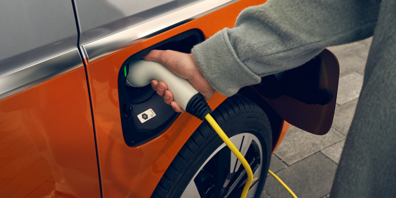 Un VW Multivan est chargé auprès d'une borne de recharge.